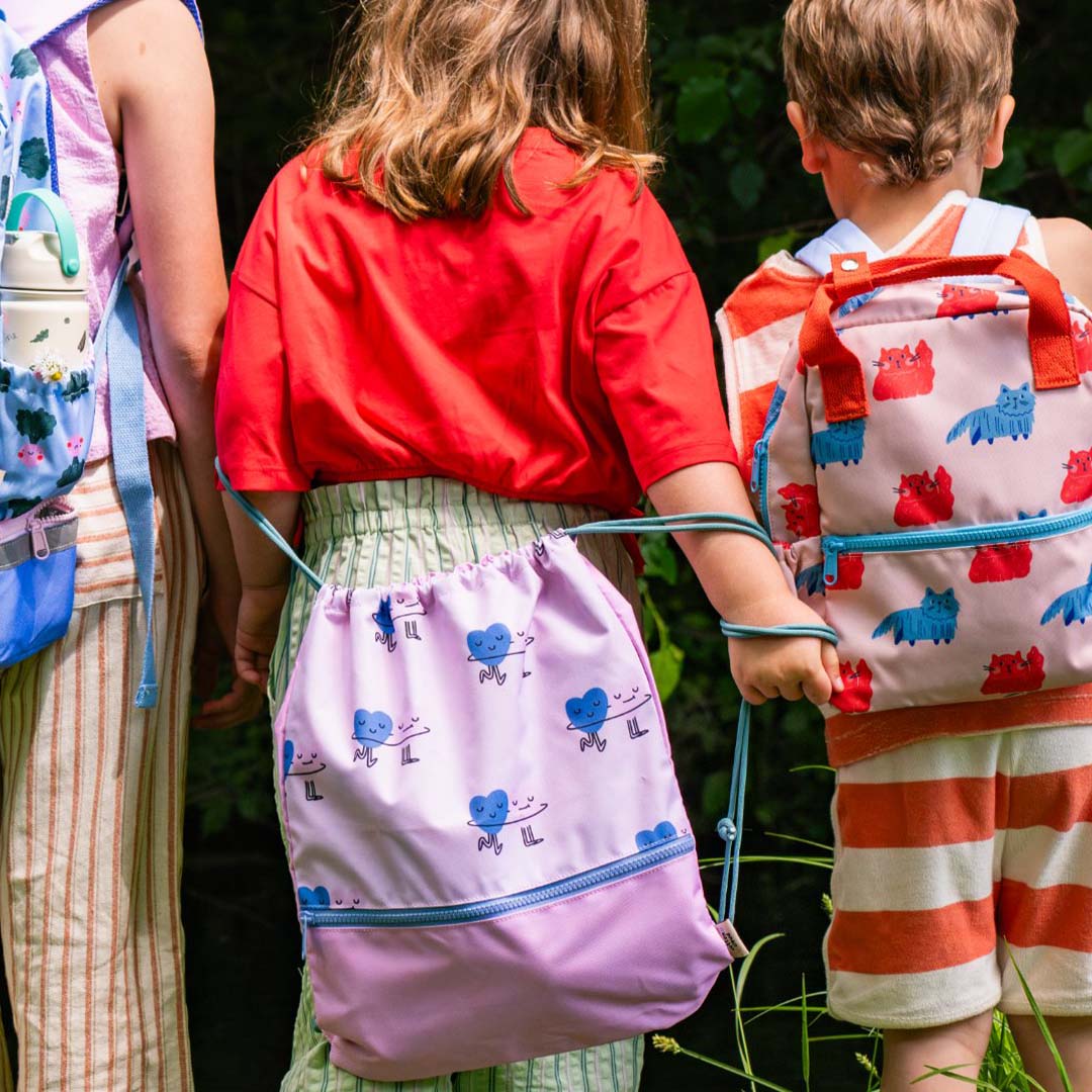 Een kind houdt de roze the cotton cloud gym- en zwemtas met dancing hearts vast, met andere kinderen ernaast.