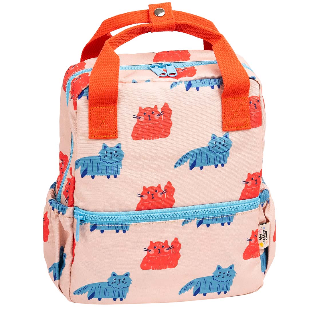De the cotton cloud kleuterrugzak met roze, rode en blauwe kattenprint en oranje handvatten.