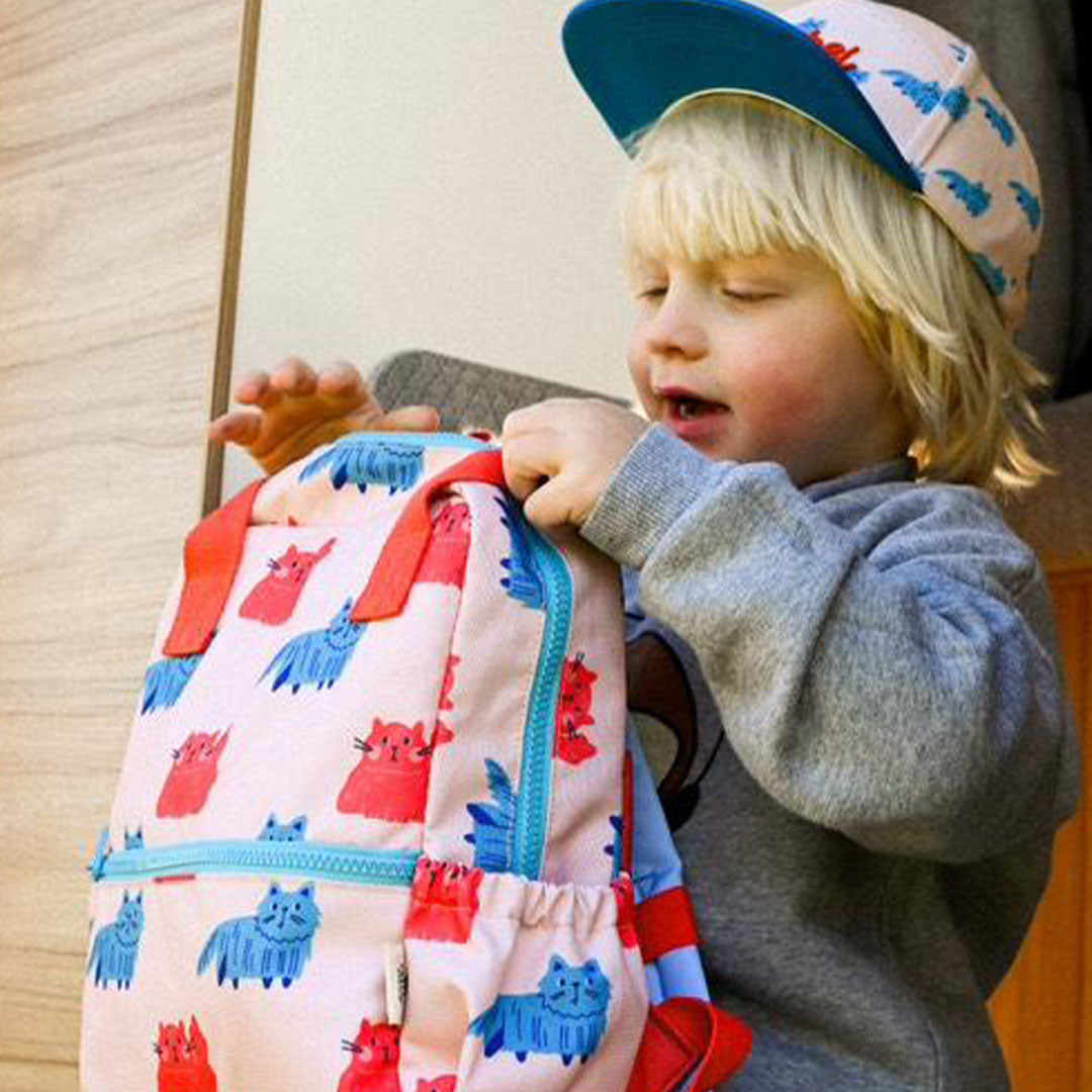 Een jong kind opent de the cotton cloud kleuterrugzak met kattenprint.