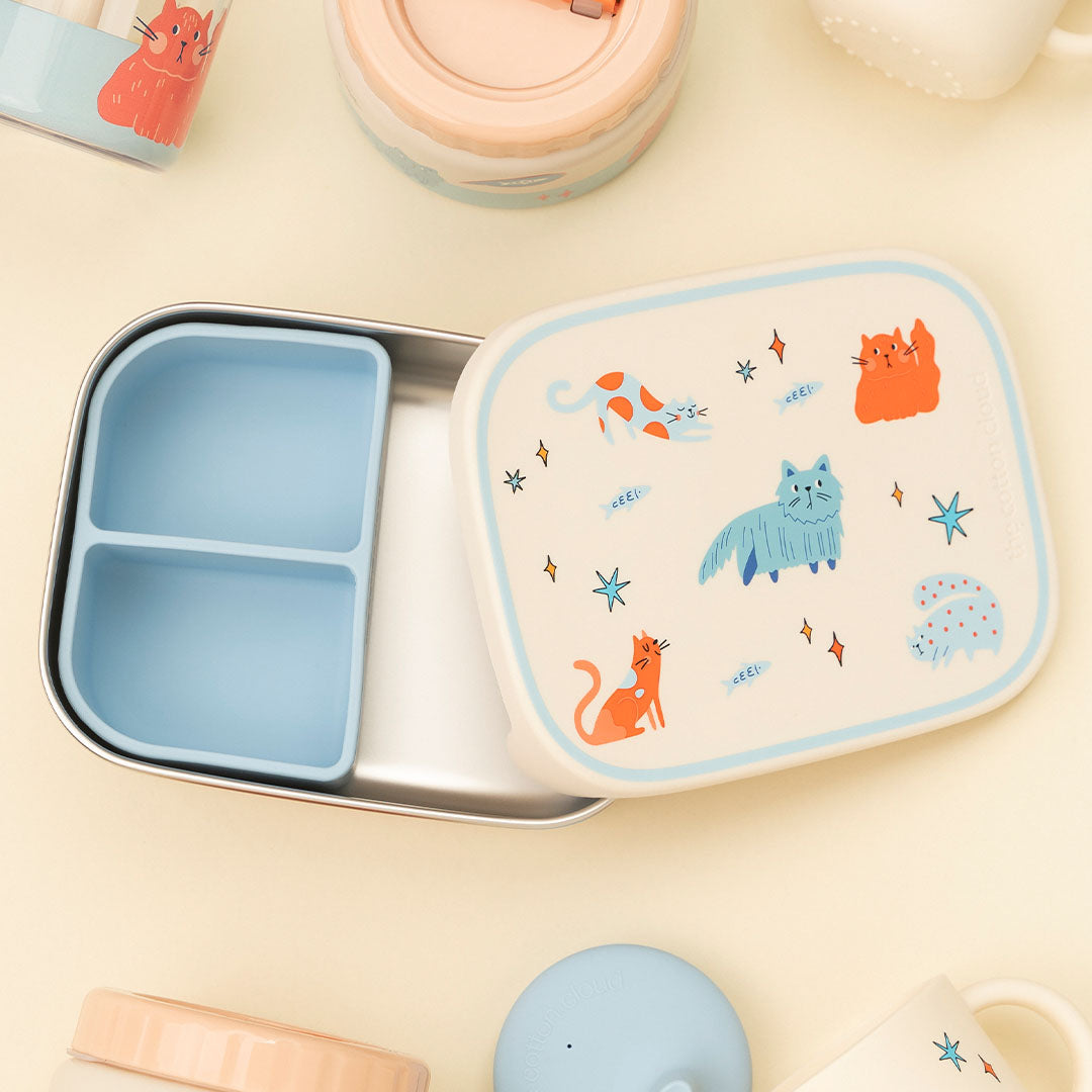 the cotton cloud rvs kinderbroodtrommel met katten en sterren, open op een lichte ondergrond met andere producten.