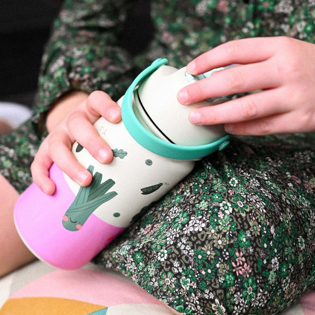 Een kind houdt een kinderdrinkfles met groentenfiguren vast.