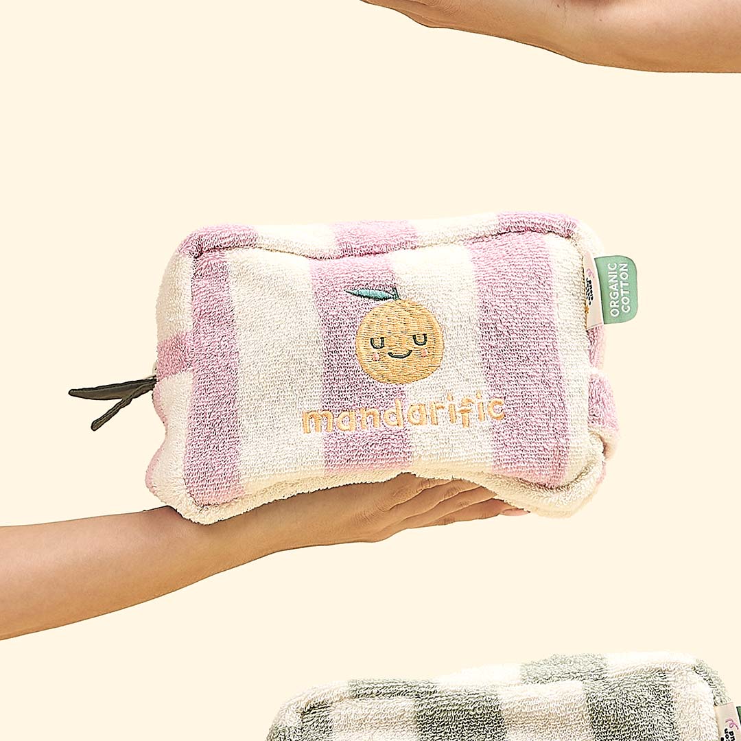 Een hand toont de The Cotton Cloud katoenen toilettas met roze-witte strepen en mandarijn.