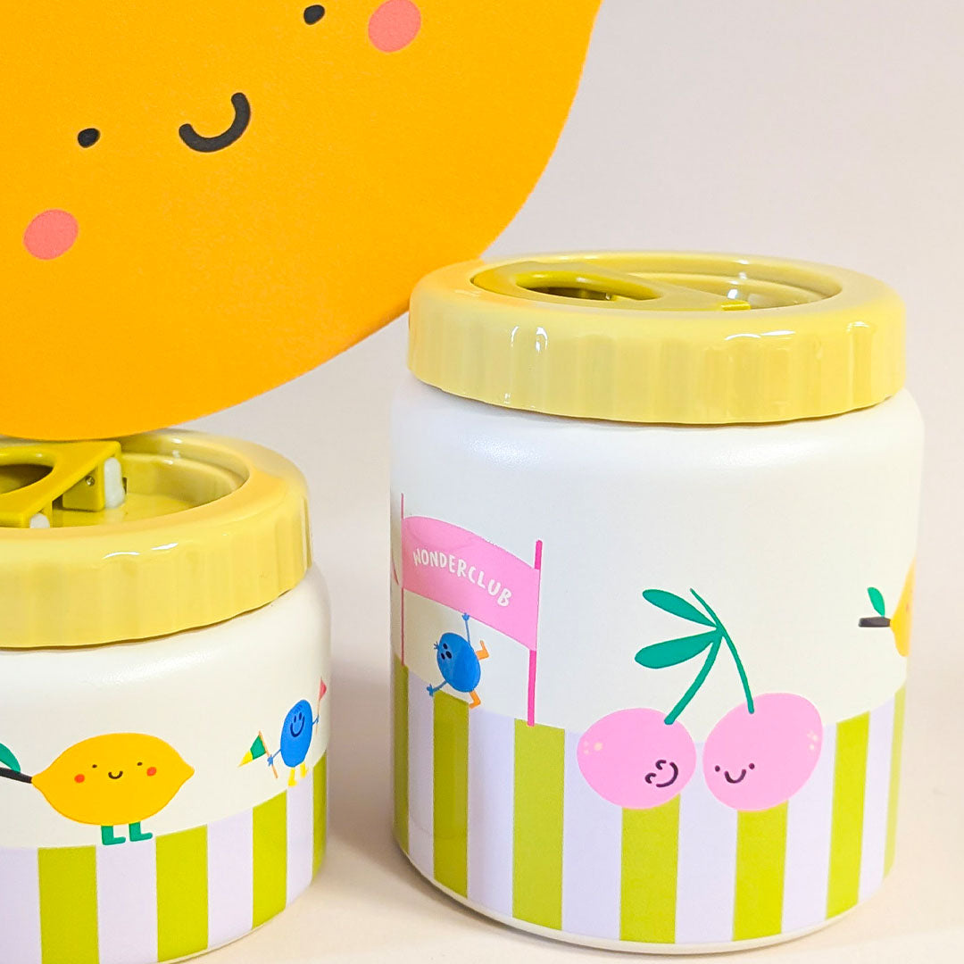 Twee the cotton cloud voedselpotten met gele deksels en een patroon van gestreepte banen, kersen en figuren, met een grote gele citroen op de achtergrond.