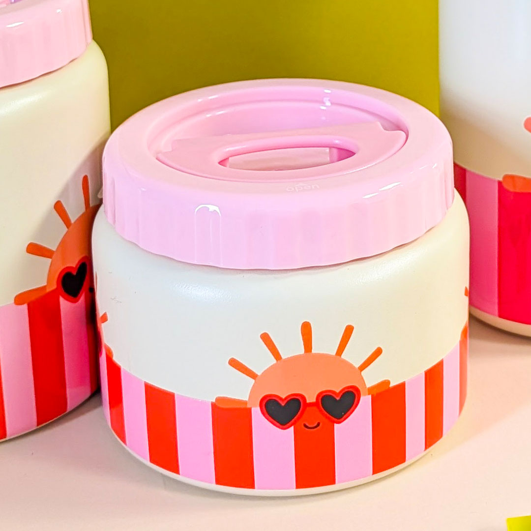 The Cotton Cloud voedselpot met roze deksel en zonnetje met zonnebril, staand tussen andere voedselpotten.