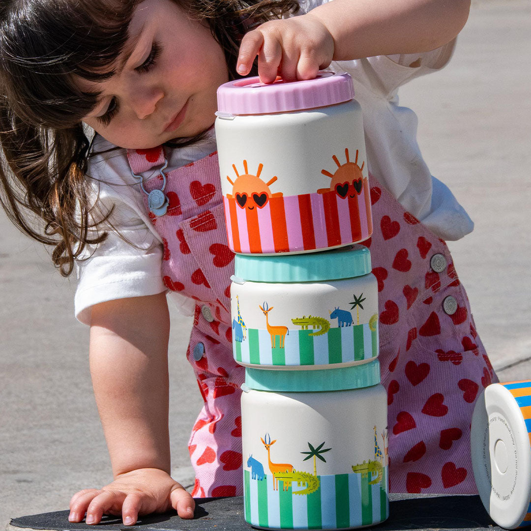 Een kind stapelt drie the cotton cloud voedselpotten met dieren- en zonpatronen.