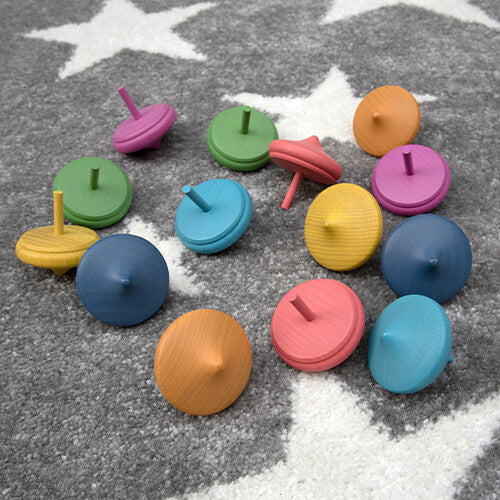 tickit houten draaitolletjes in regenboogkleuren verspreid over een grijs vloerkleed met sterren.