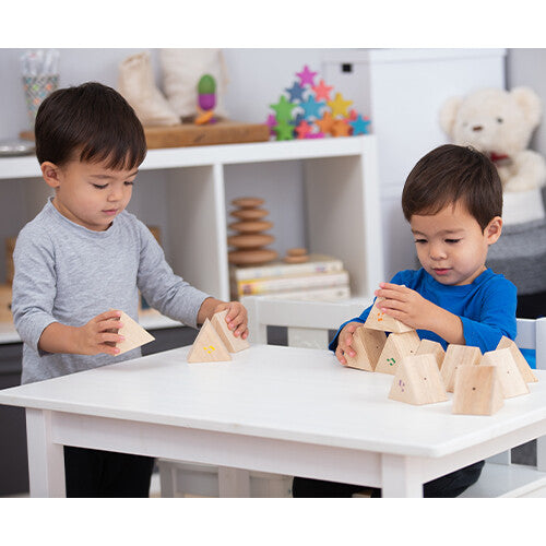 Twee kinderen spelen samen met Tickit houten geluiden memorie prismablokken aan een witte tafel.