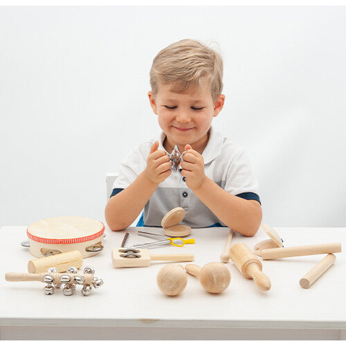 Een lachende jongen speelt met een metalen shaker uit de tickit muziekinstrumenten set.