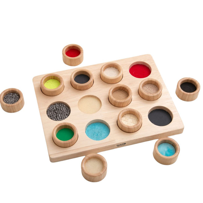 Tickit sensorisch sorteerspel met houten bord en losse cups met verschillende texturen en kleuren.