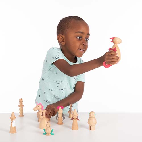 Een jongen speelt met de tickit houten sprookjesfiguren, hij houdt de draak vast.