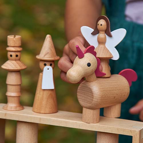 Een kinderhand pakt de tickit houten eenhoorn uit de sprookjesfiguren set.
