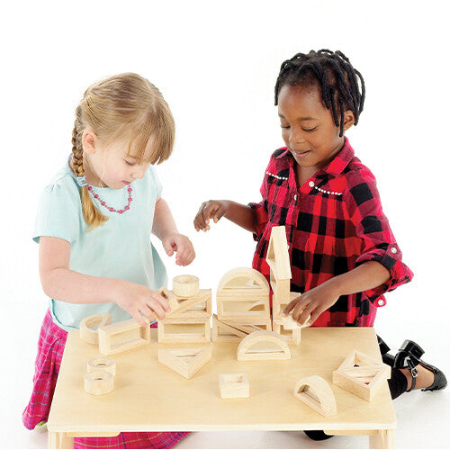 Twee kinderen bouwen met tickit houten spiegelblokken op een houten tafel.