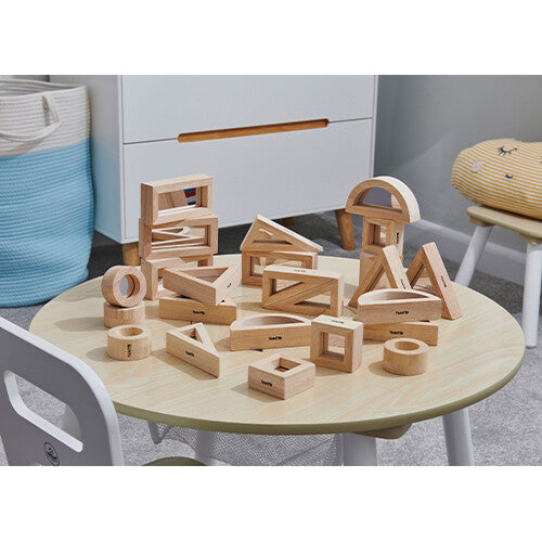 Een collectie tickit houten spiegelblokken op een ronde houten tafel in een kinderkamer.