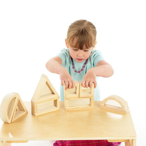 Een kind bouwt met tickit houten spiegelblokken op een houten tafel.