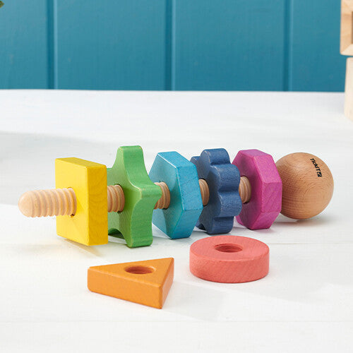 tickit houten vormen twister met losse regenboogkleurige geometrische vormen op een tafel.