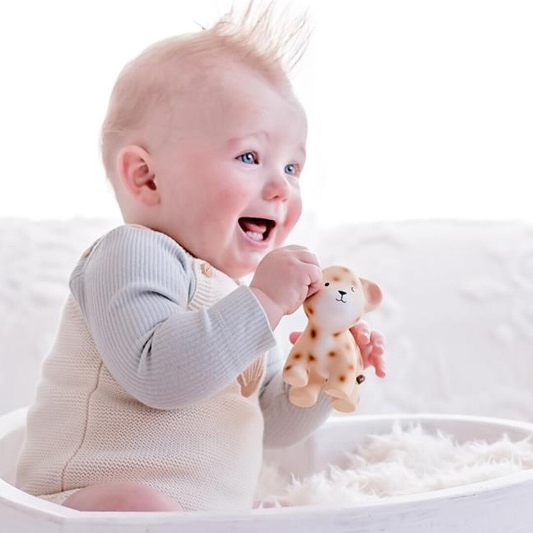 Een lachende baby houdt het Tikiri luipaard bijtspeelgoed vast.
