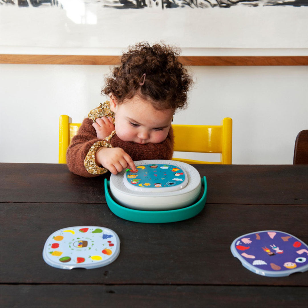 Een kind kijkt geconcentreerd naar de Timio educatieve audiospeler met een onderwater-thema schijf.