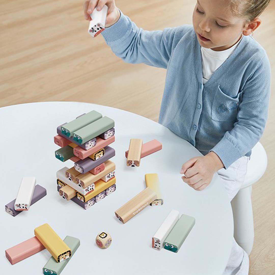 Een kind speelt met het Topbright wiebeltoren dierenspel aan een witte tafel.