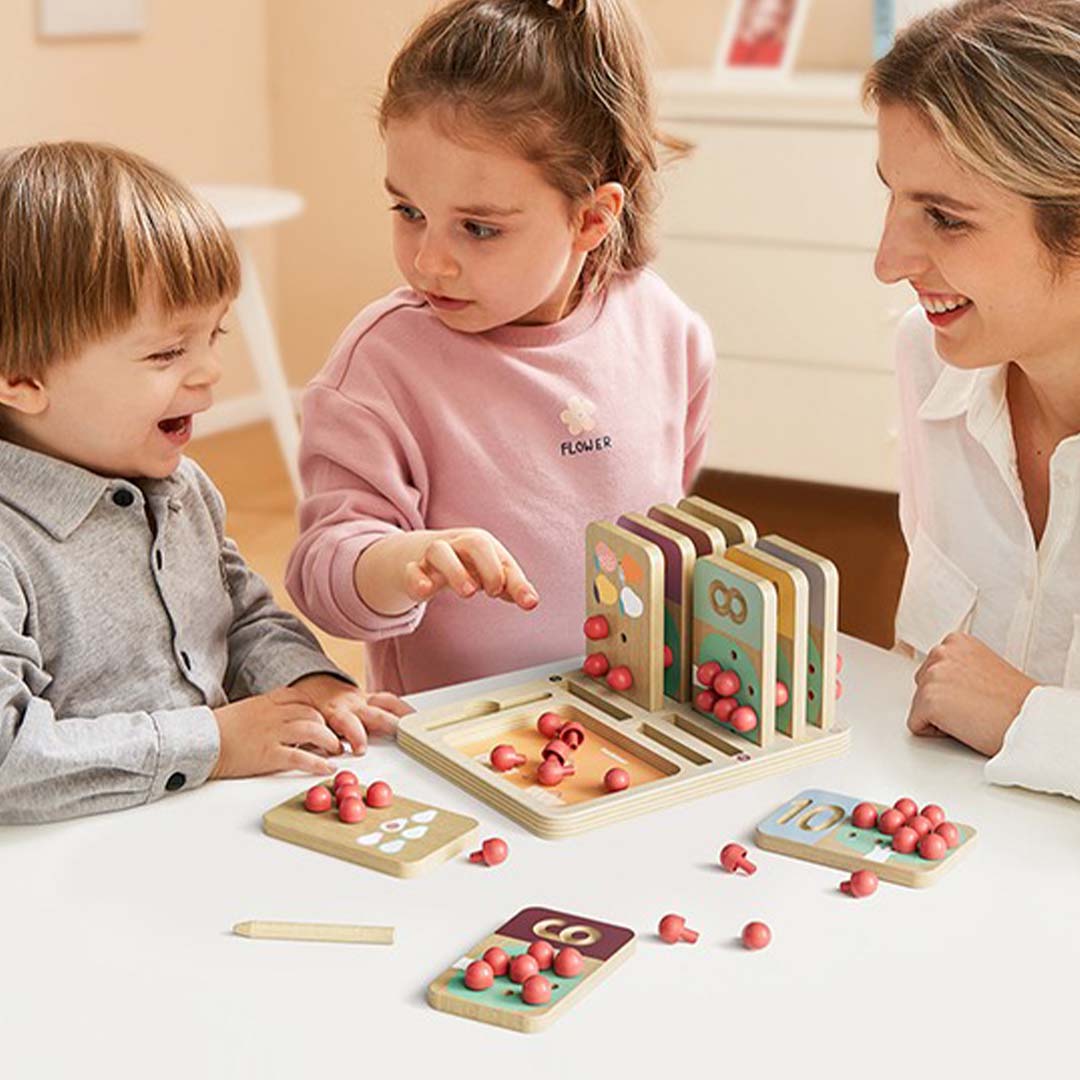 Een vrouw en twee kinderen spelen samen met het Topbright educatieve telspel fruitboom aan een witte tafel.