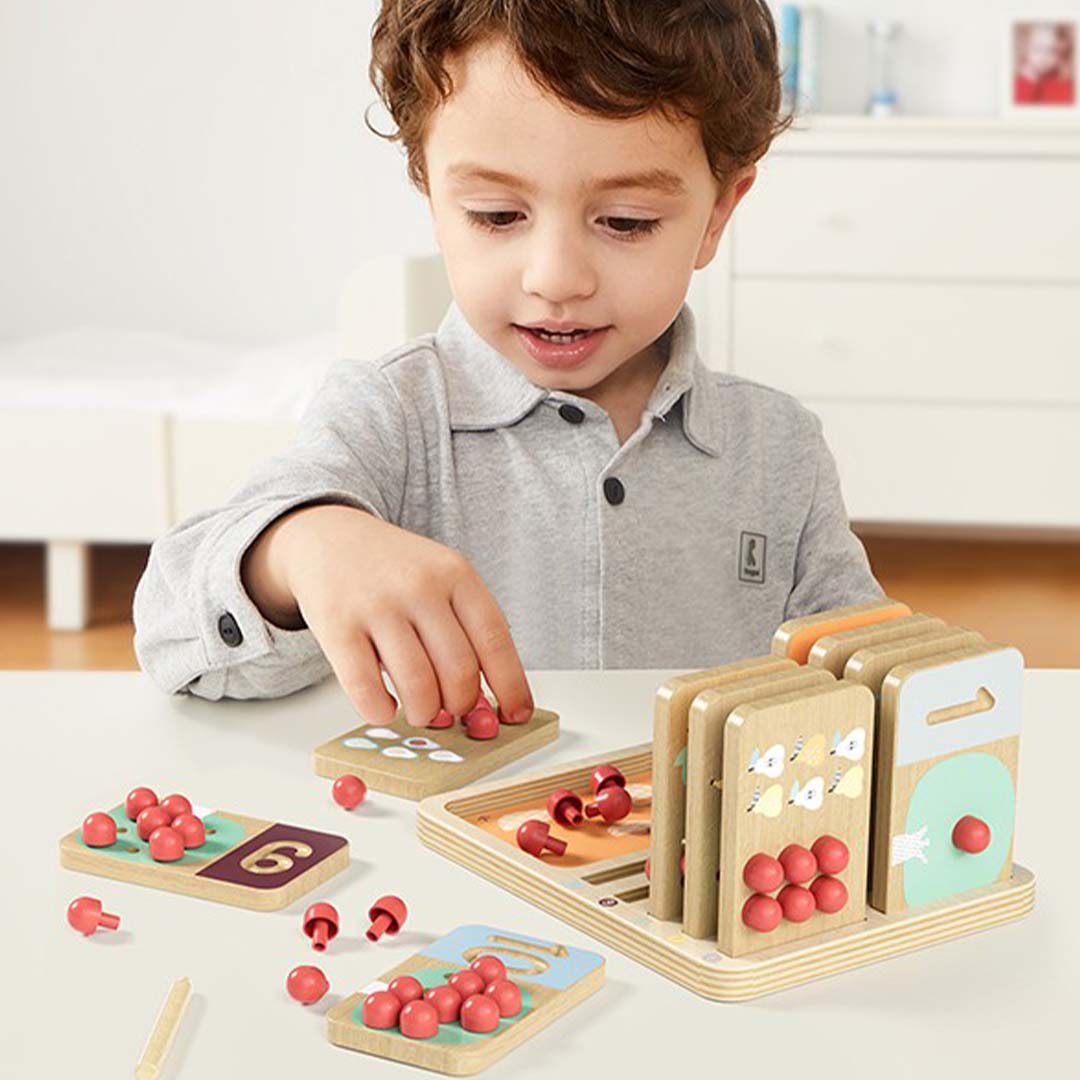 Een jongen speelt met het Topbright educatieve telspel fruitboom en plaatst een rode pion op een cijferkaart.