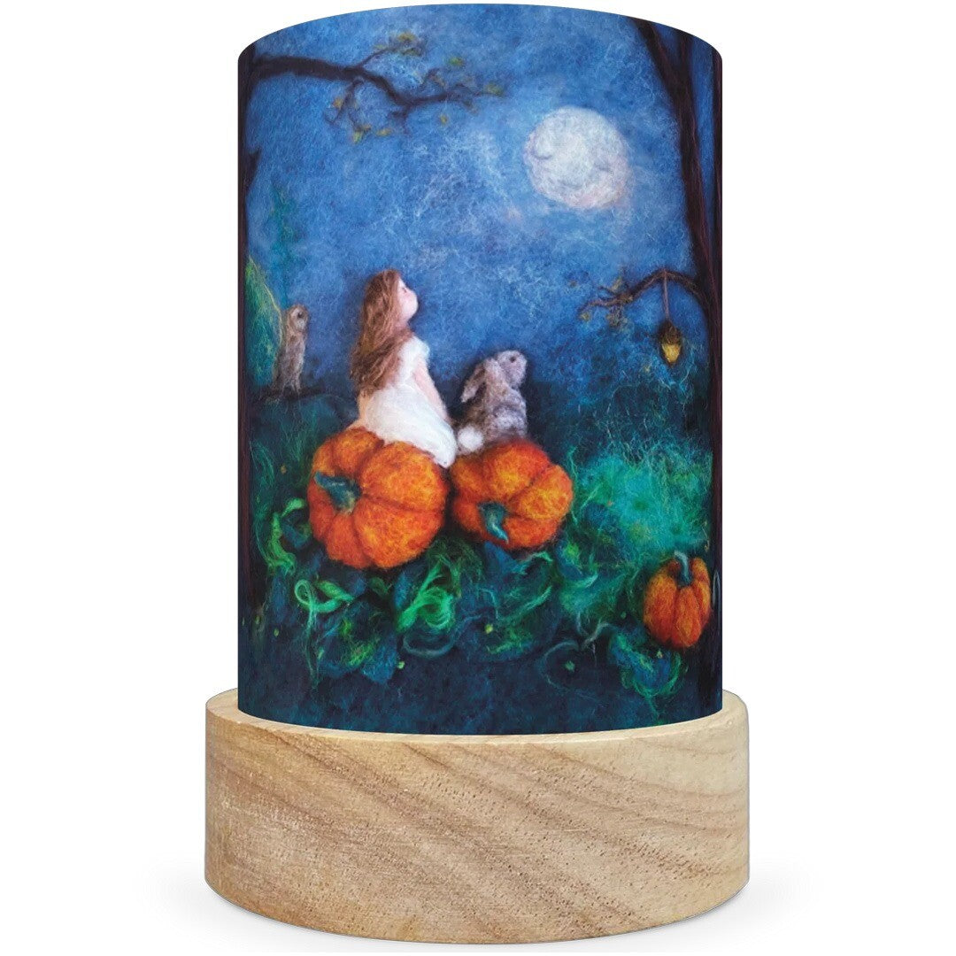 Een Toverlux lichtkaart met een meisje en een konijn die op pompoenen zitten onder een volle maan.
