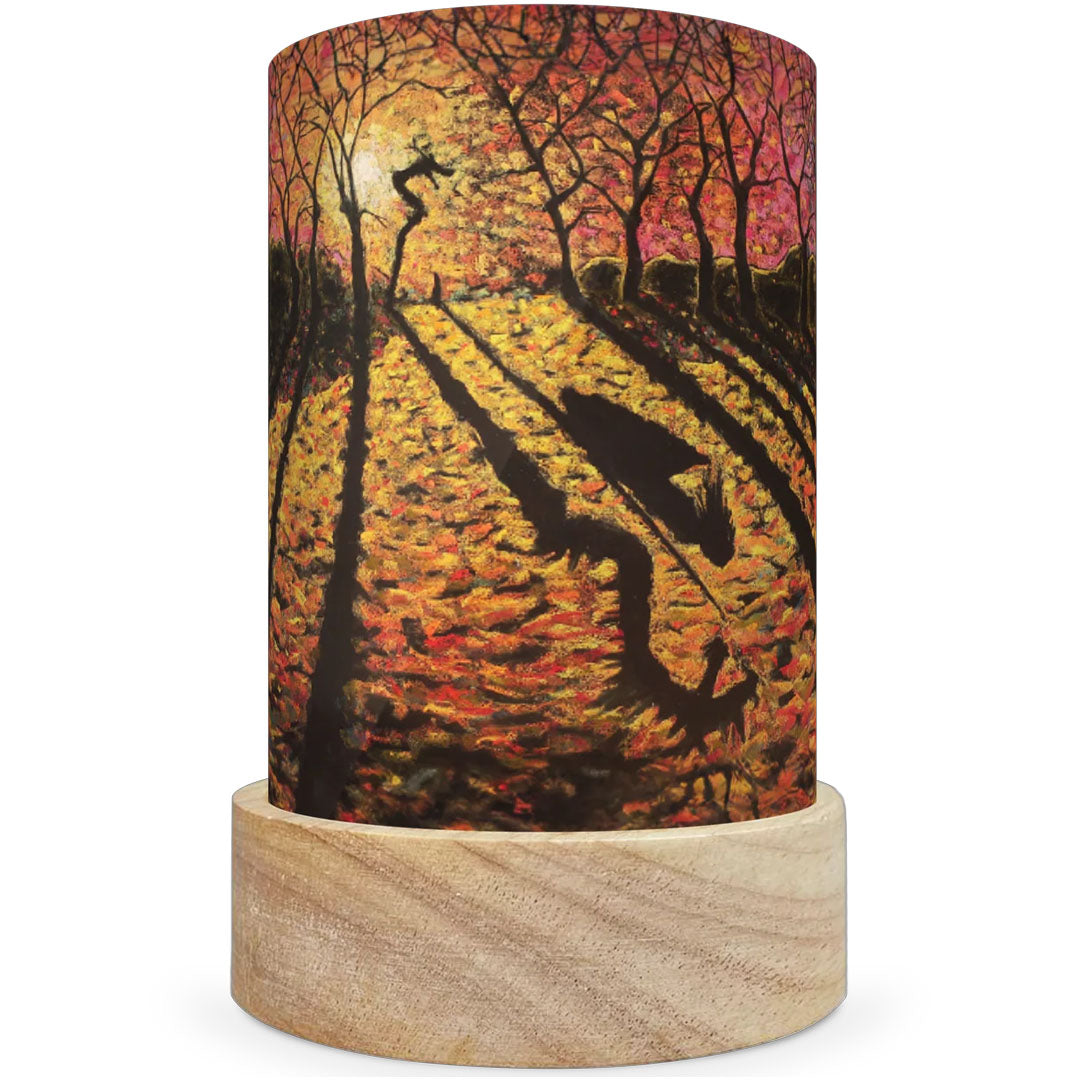 Toverlux lichtkaart met een illustratie van een herfstbos met kale bomen, lange schaduwen en oranje bladeren.