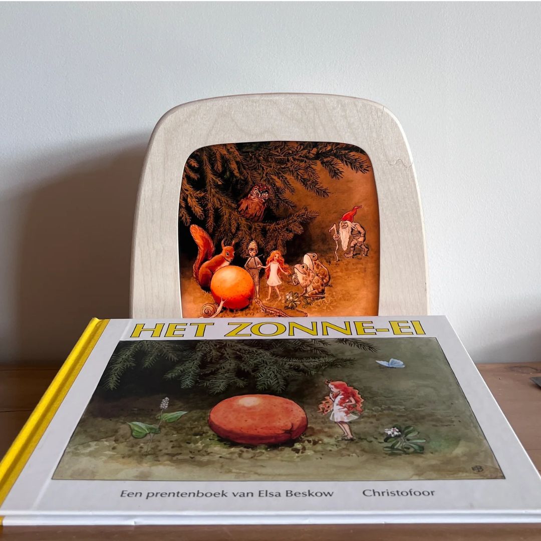 Een Toverlux toverplaat met een bosbijeenkomst van dieren en figuren, staand achter het prentenboek 'Het Zonne-ei'.