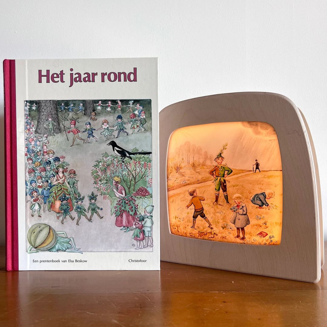 Toverlux toverlamp met de illustratie van kinderen en een nar, naast het boek 'Het jaar rond' van Elsa Beskow.