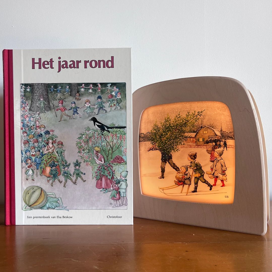 Toverlux lamp met de winterse kerstscène naast het prentenboek 'Het jaar rond' van Elsa Beskow.