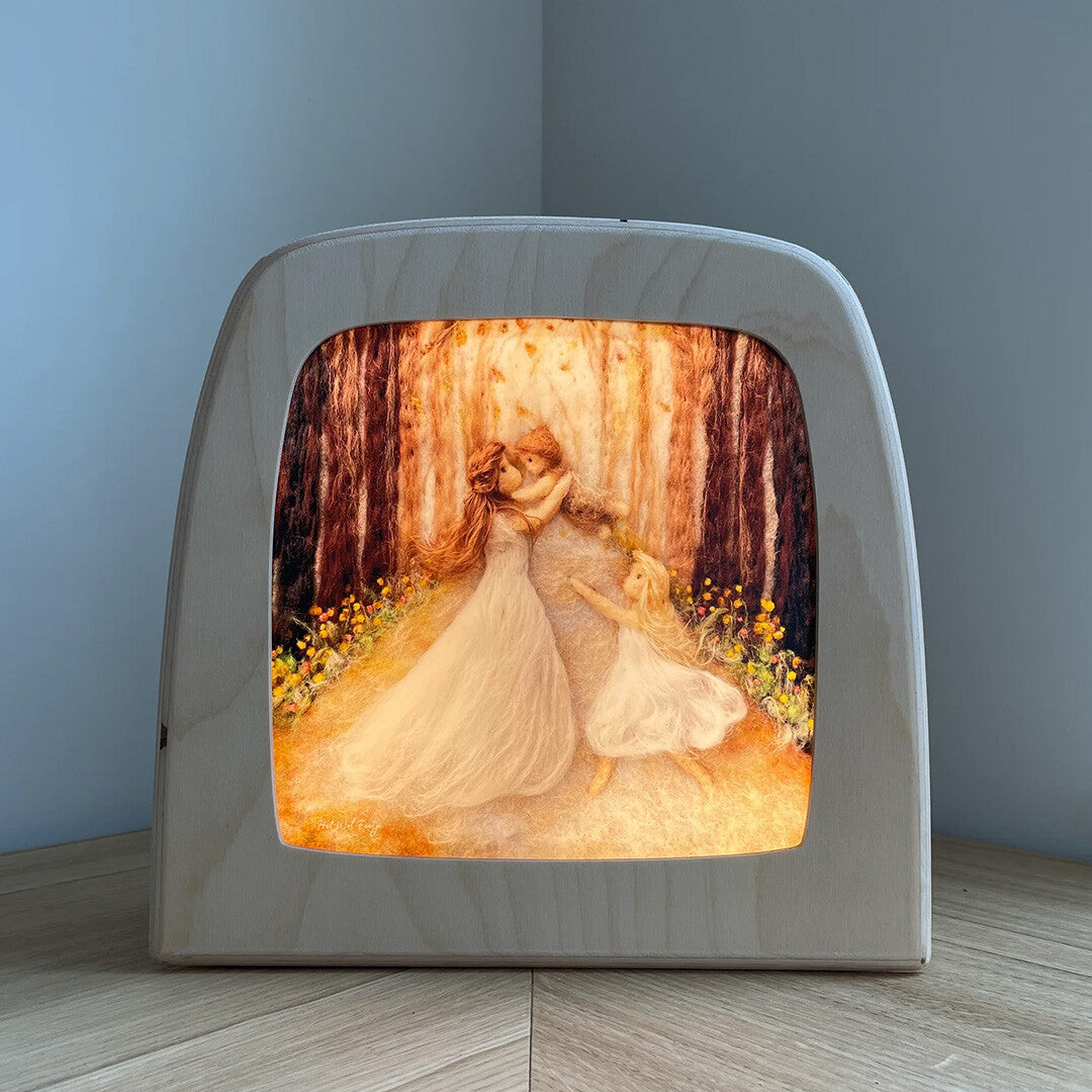 De Toverlux toverlamp met de verlichte toverplaat 'moeder met kinderen' in een bos van vilt.
