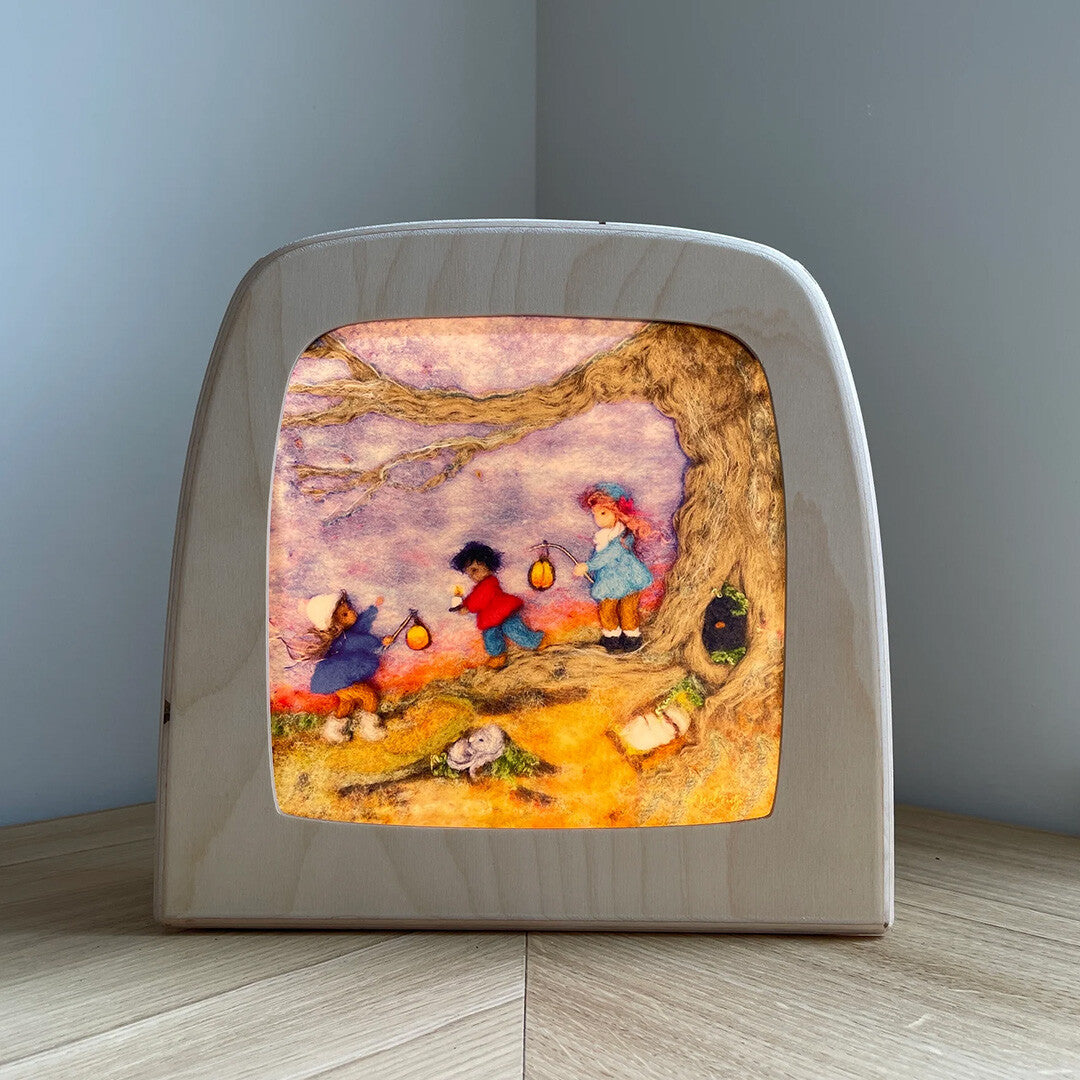 Vooraanzicht van de Toverlux toverlamp met de Sint Maarten toverplaat, verlicht op een houten ondergrond.