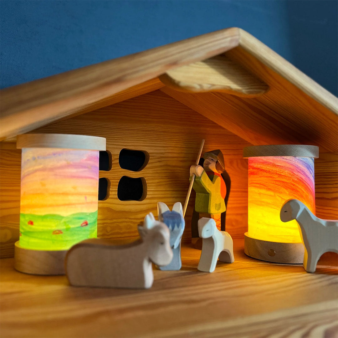 Toverlux lantaarns in een houten kerststal met houten figuurtjes.