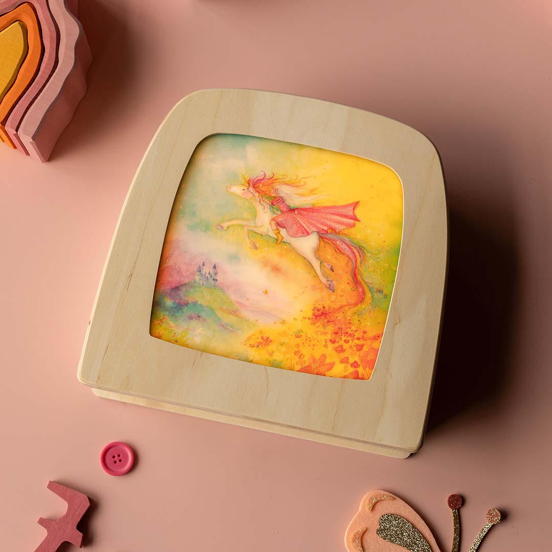 Toverlux toverplaat met een eenhoornillustratie in een houten frame, liggend op een roze ondergrond.
