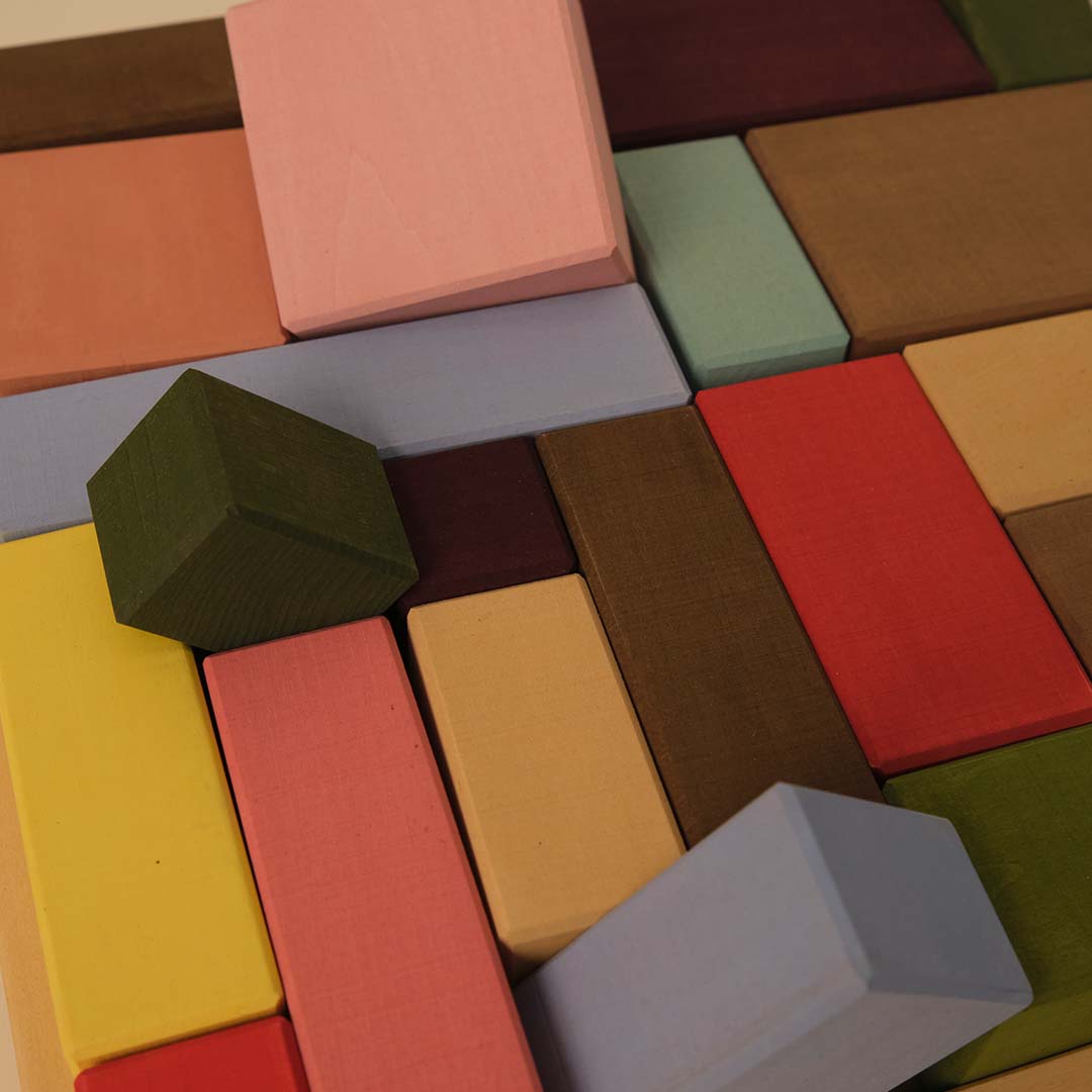 Detailopname van toyto houten bouwblokken in diverse pastelkleuren en vormen.