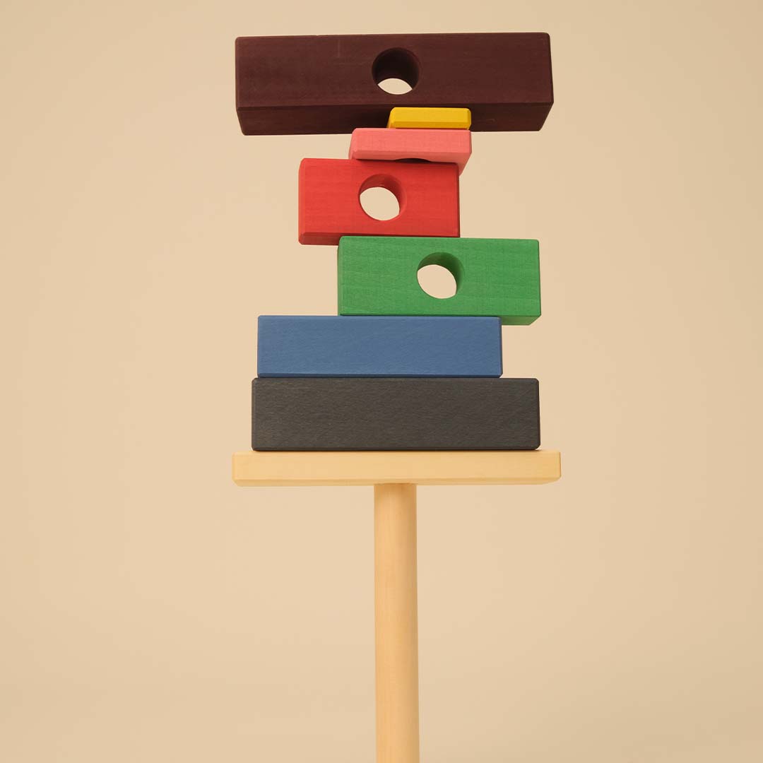 Een toyto houten stapeltoren met veelkleurige blokken en een houten pin, recht van voren gefotografeerd.