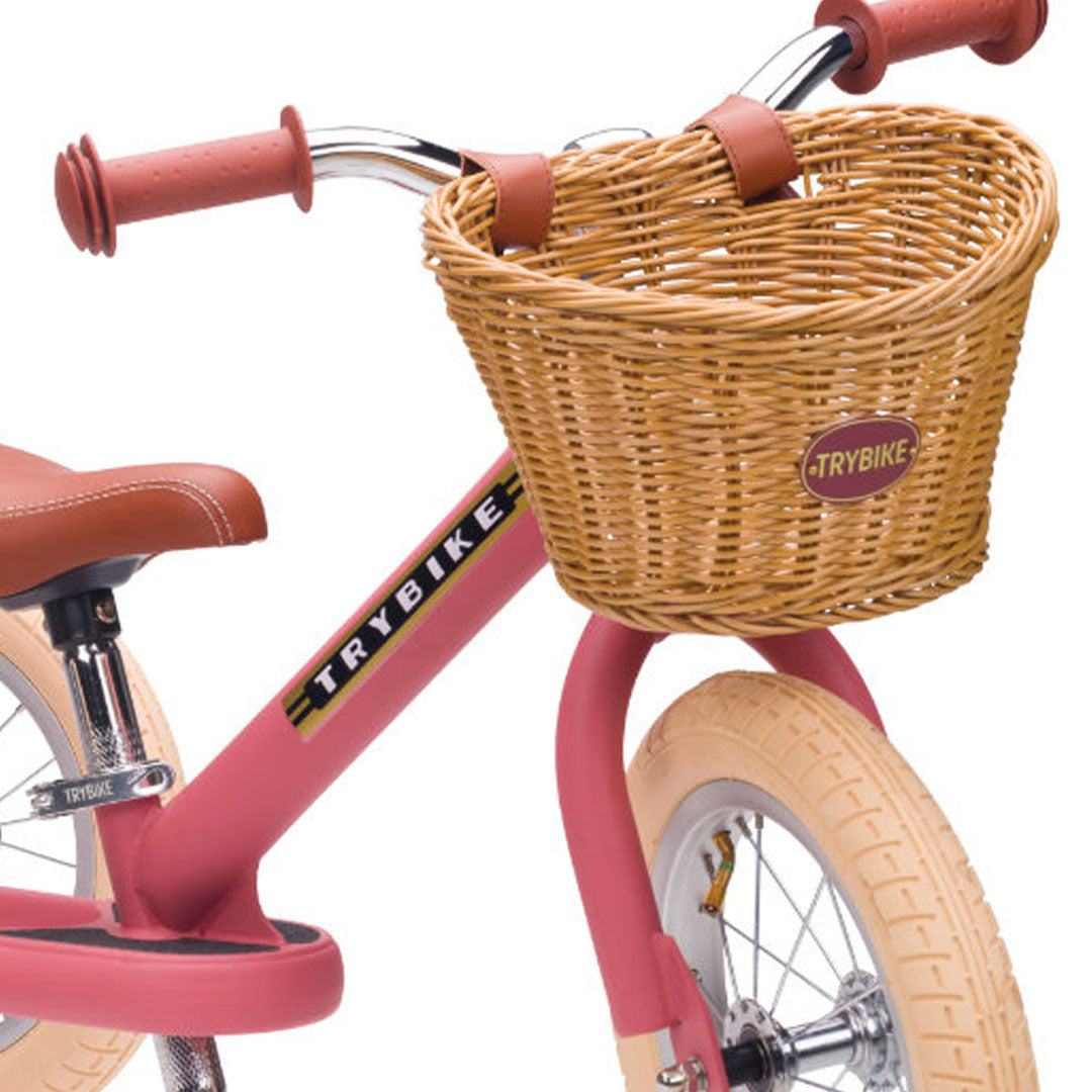 Trybike gevlochten kinderfietsmandje gemonteerd op het stuur van een roze loopfiets.