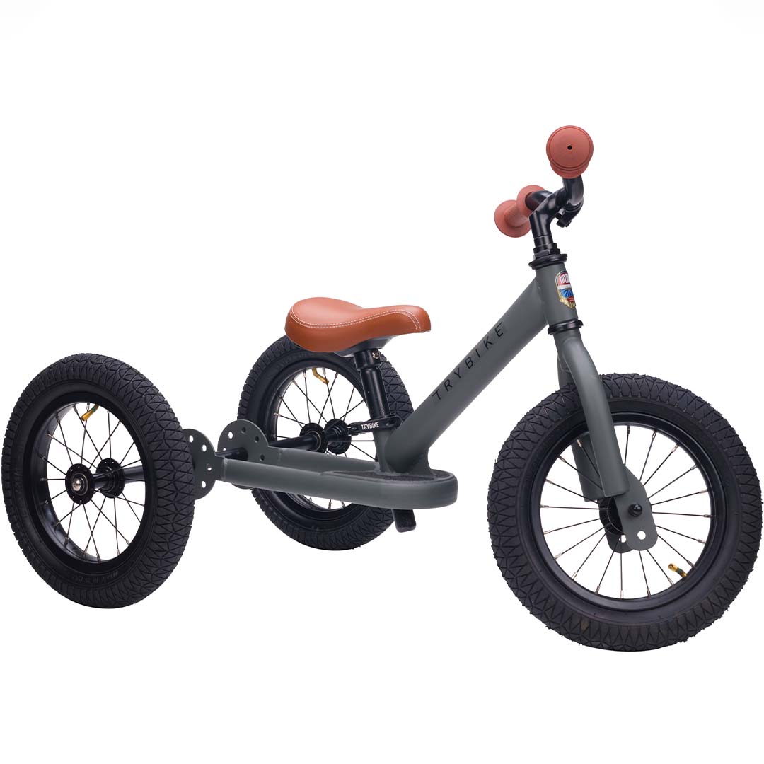 Trybike stalen 2-in-1 loopfiets in driewielerstand, grijs met bruine zitting en handvatten.