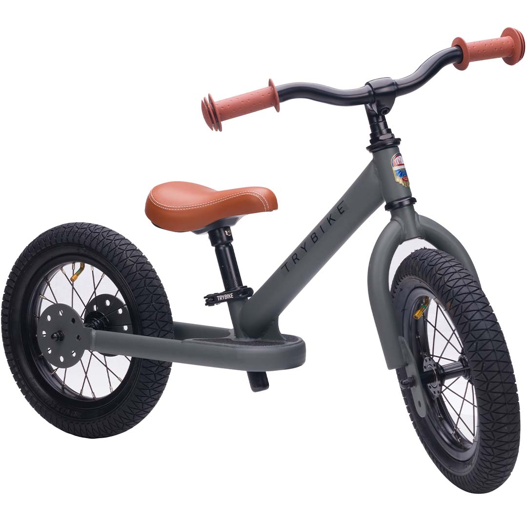 Trybike stalen 2-in-1 loopfiets in tweewielerstand, grijs met bruine zitting en handvatten.