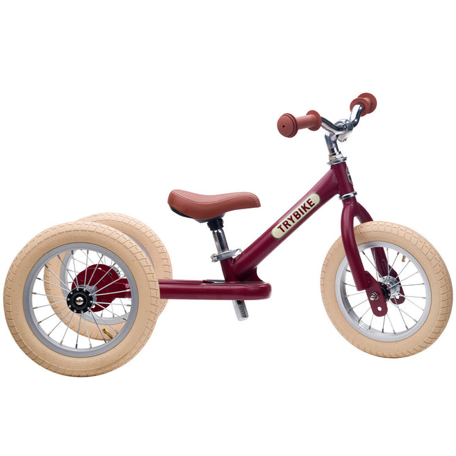 Trybike 2-in-1 loopfiets in vintage rood mat met bruine accenten, opgesteld als driewieler.