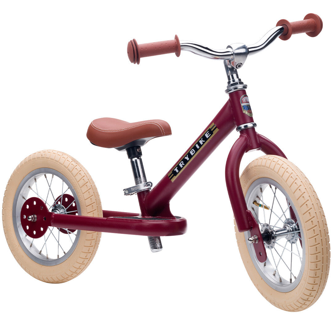 Trybike 2-in-1 loopfiets in vintage rood mat met bruine accenten, opgesteld als tweewieler.