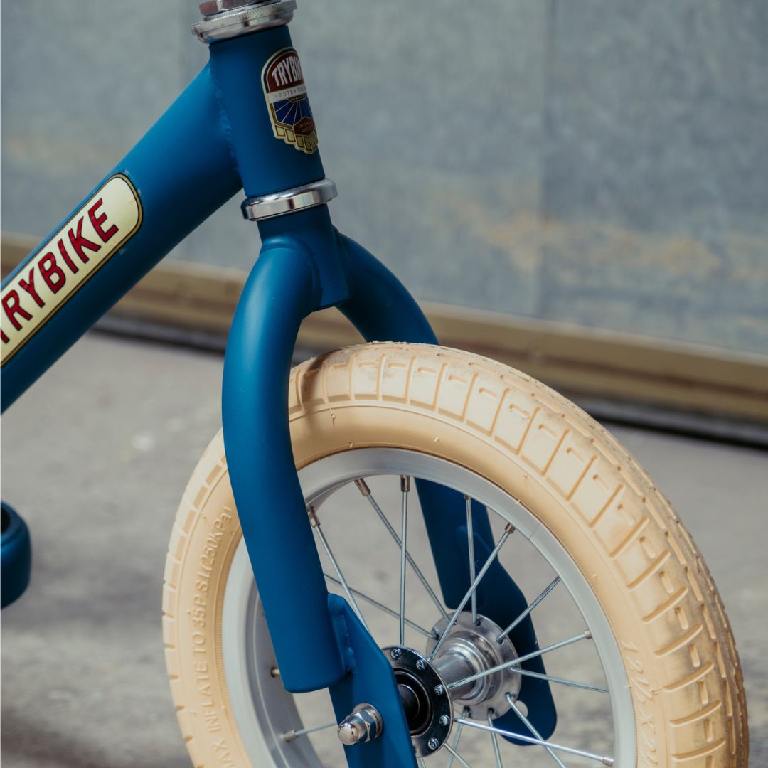 Detail van de Trybike stalen loopfiets met de vintage blauwe voorvork en een crème band.