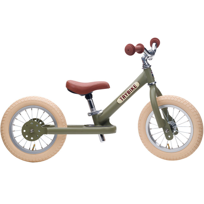 Trybike stalen loopfiets in vintage groen met bruin zadel en crèmekleurige banden.