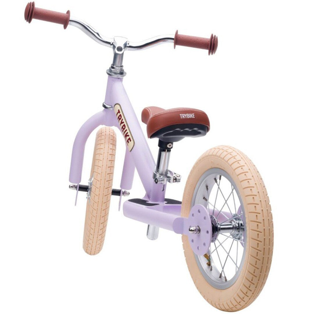 Achteraanzicht van de lila Trybike stalen loopfiets met bruine zitting en handvatten, op een witte achtergrond.