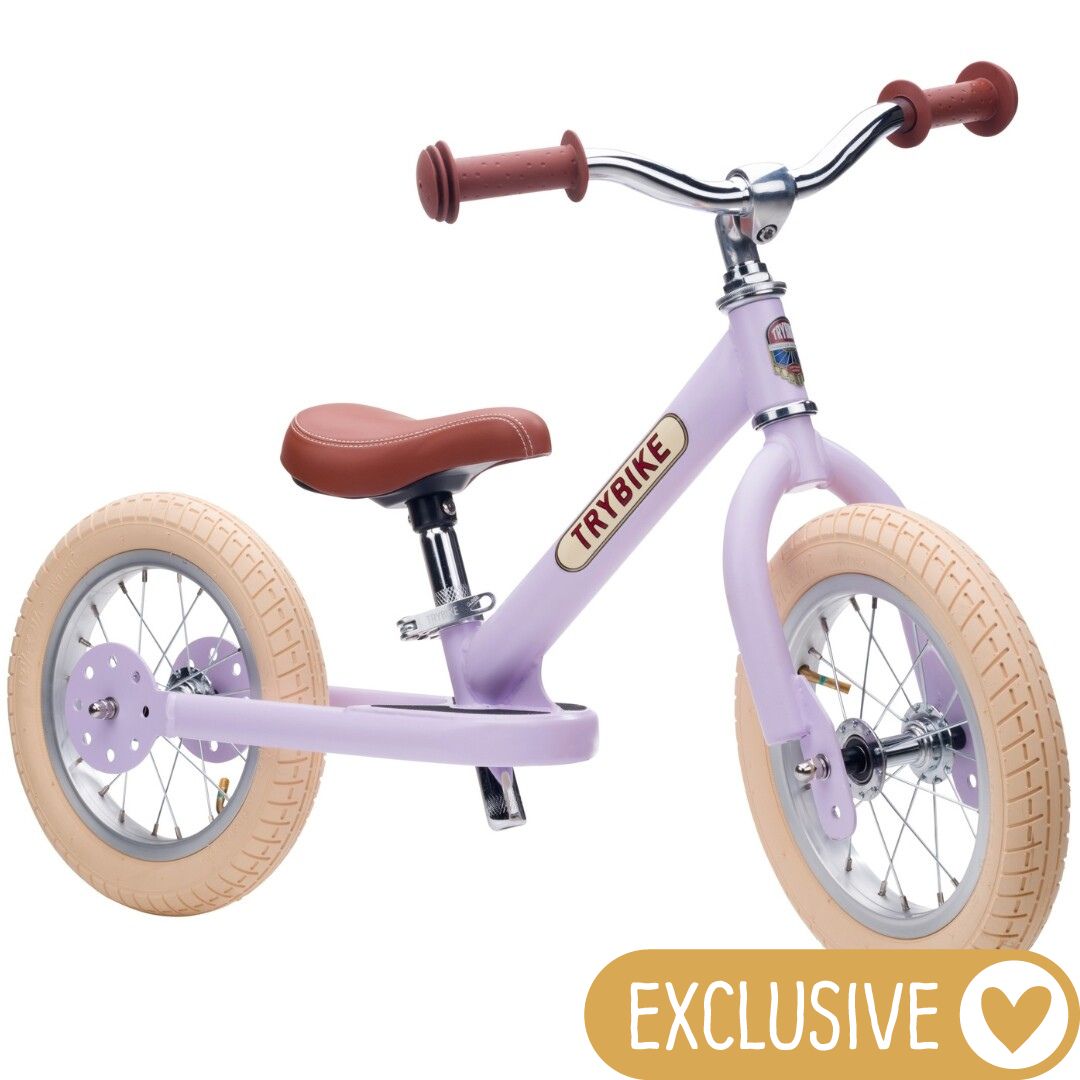 Trybike stalen loopfiets in vintage lila met bruine zitting en handvatten, op een witte achtergrond.