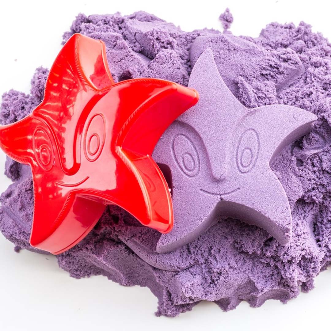 Een rode plastic zandvorm van een zeester en een paarse zeester gemaakt van kinetisch zand.