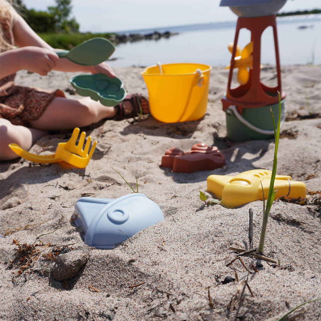 Een kind speelt op het strand met Viking Toys re:line zandvormpjes en ander zandspeelgoed.