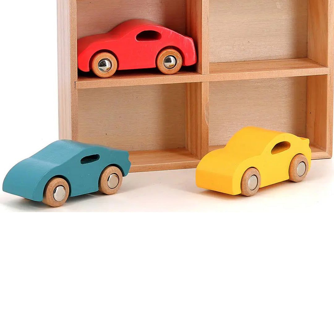 Drie Vilac houten speelgoedauto's in rood, blauw en geel, de rode staat op een houten plank.