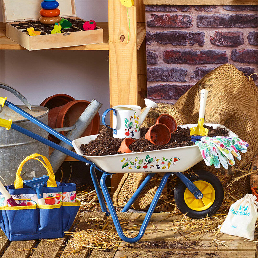 Vilac kinderkruiwagen gevuld met aarde en tuingereedschap in een tuinsetting.
