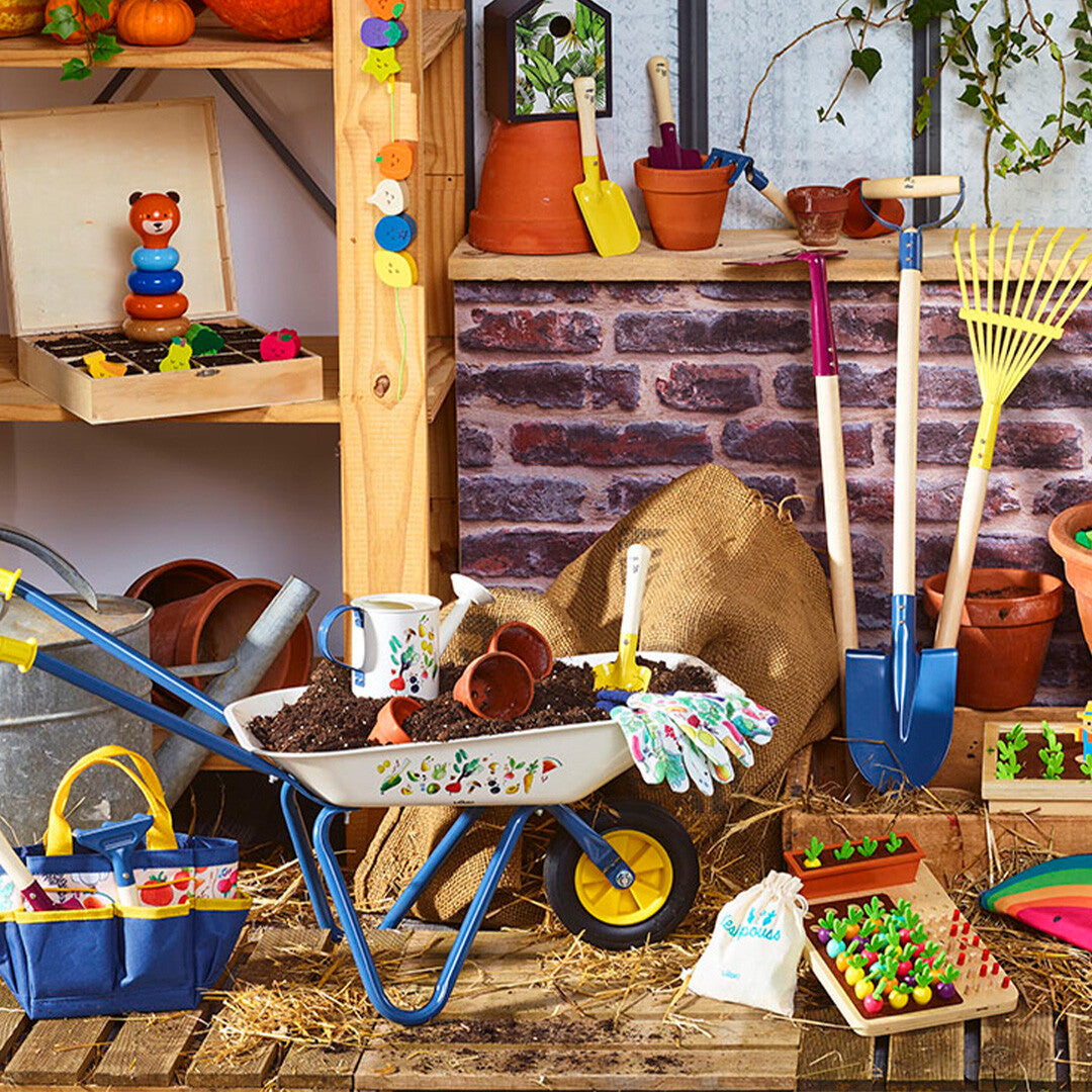 Vilac kinderkruiwagen in een tuinsetting met diverse tuinspeelgoed zoals scheppen en potten.