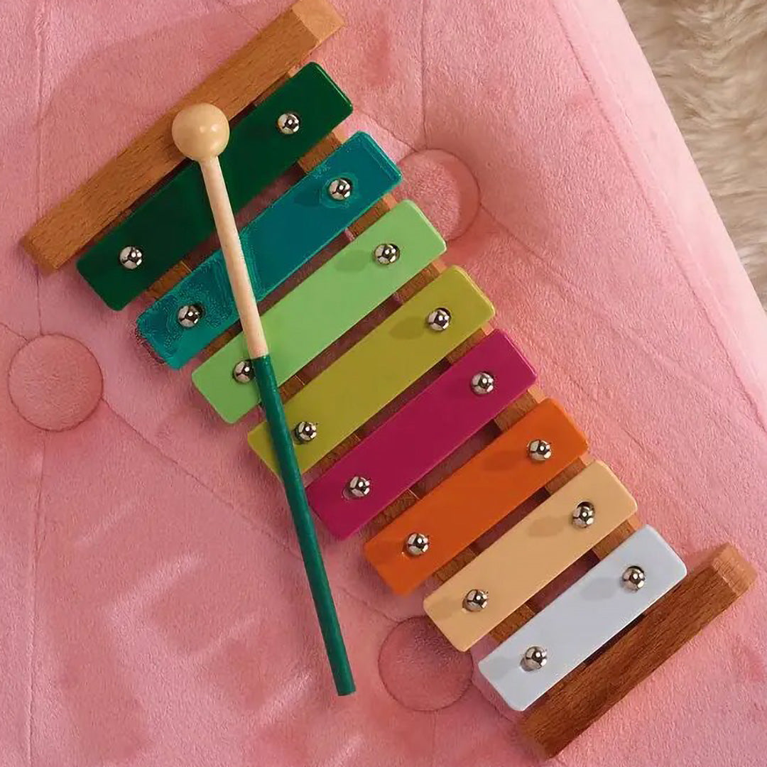 Een kleurrijke houten xylofoon met acht gekleurde toetsen en een slagstokje.